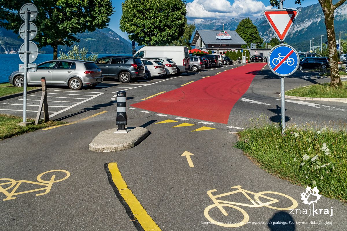 Czerwony pas dla rowerzystów przez środek parkingu